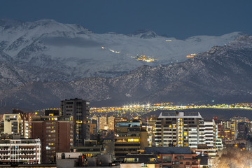 Amazing views of Santiago de Chile skyline by night with the Andes mountain range full of snow and...
