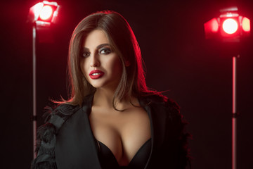 Sexy woman with nice figure posing on dark red lights background.