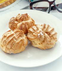 Fresh brewed cakes with protein cream on a white porcelain plate. Sweet treat for midday tea
