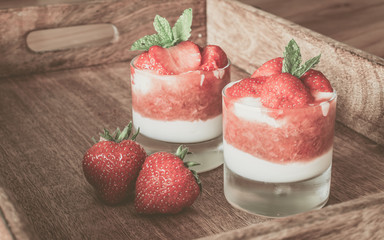 Strawberry dessert in small glasses on wooden tray. Vintage photo.
