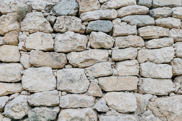 Gray grungy ancient stone wall in Spain. Stones with different shapes