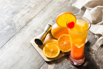 Tequila sunrise cocktail in glass on wooden table. Copyspace