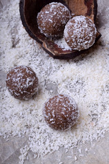 Ball-shaped sweets sprinkled with coconut flakes on a piece of parchment paper