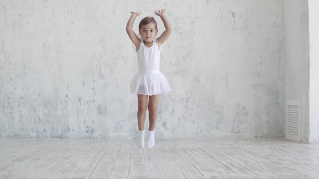 a small ballerina in a white pack jumps up. slow motion