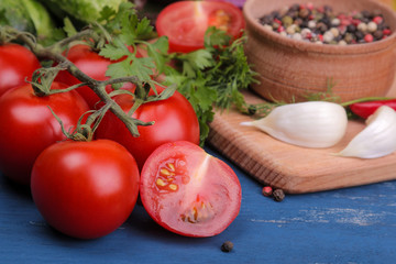 Tomatoes are greenery of garlic and spices. fresh vegetables. ingredients for cooking. on a blue wooden table