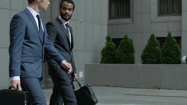 Young entrepreneurs leaving business center, discussing news, end of work day