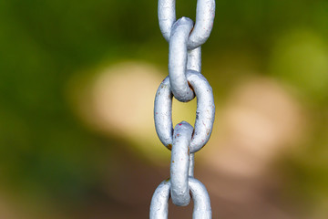 Metal chain close-up stretching down in blurred background