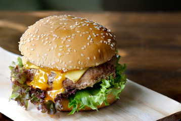 Hamburger on chopping board on dark wooden background