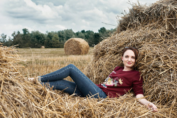 young girl having fun in the field, lying on a haystack