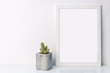 White mockup frame with a cactus in a concrete flowerpot on an empty white background