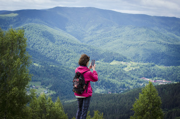 Naklejka premium girl in the mountains shoots on the phone