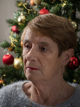 Sad Elderly Woman By A Christmas Tree