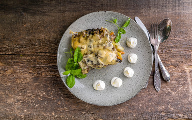 Julienne with mushrooms, cheese and herbs on a wooden background. Top view
