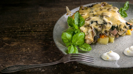 Julienne with mushrooms, cheese and herbs on a wooden background. Close Up