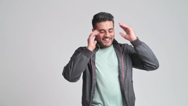 Bearded hipster dancing portrait. Young indian man in autumn clothing dancing in front of camera. Hipster lifestyle concept.