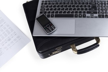Cell phone sitting on top of a laptop and briefcase