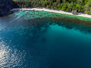 Beautiful white sandy beach with turquoise sea water and palm trees. A view from above with the help of an air dron.