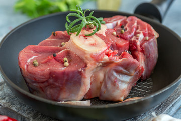 Piece of raw beef shank for Osso Buco and a sprig of rosemary.