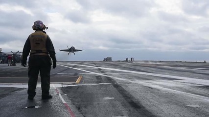 A jet airplane makes a touch and go pass over an aircraft carrier.