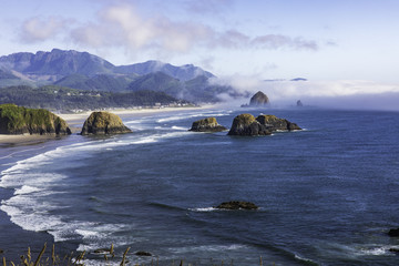 Haystack Rock with fog behind it as seen from Ecola State Park