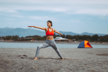 Obraz premium Young woman practicing yoga on the beach