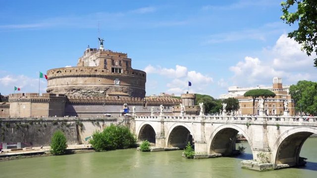 View of medieval St. Angelo castle from the other side of Tiber river. Castello Sant'Angelo fortress and bridge on sunny day in Rome, Italy in slow motion