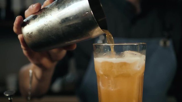 Young professional bartender preparing cocktails outside Close up Slow motion pouring shaker lemonade