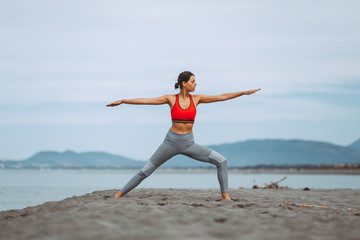 Young woman practicing yoga on the beach