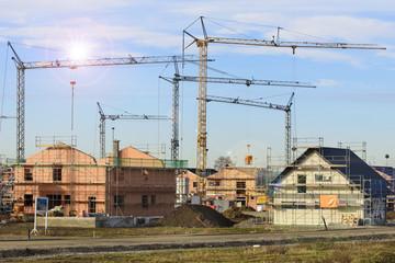 Neubaugebiet mit vielen Häusern im Rohbau und Baukräne