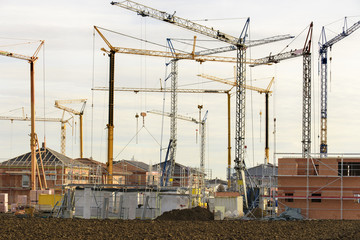 Neubaugebiet mit vielen Häusern im Rohbau und Baukräne