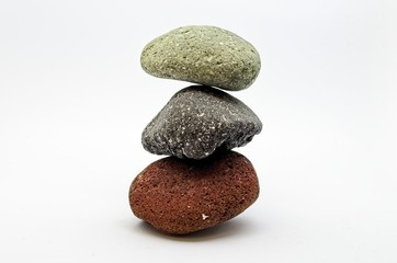 Fototapeta na wymiar Pyramid of three colored stones over white background