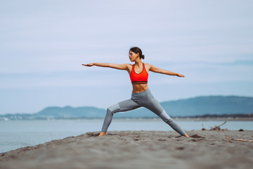 Fototapeta premium Young woman practicing yoga on the beach