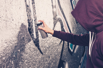 Graffiti-Künstler mit Aerosol-Sprühflasche in der Nähe der Wand