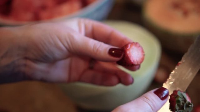Woman cutting strawberries in her hand, in slow motion