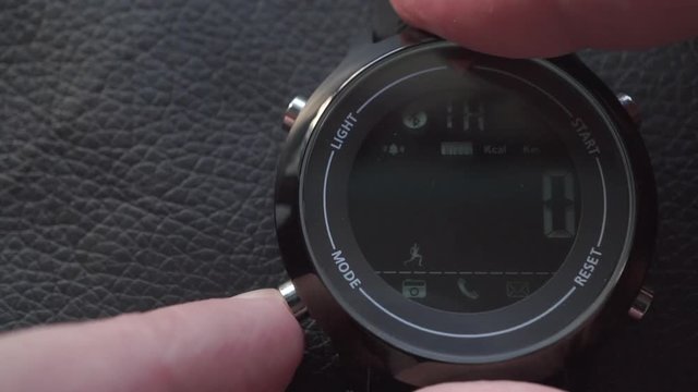 pressing buttons switching modes on sport smart watch with natural black leather background. macro close-up shot