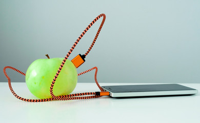 Green apple connected by an orange cable to a phone