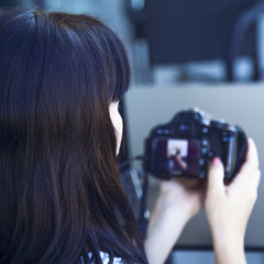 Young female photographer viewing his photos on the back of the camera LCD display