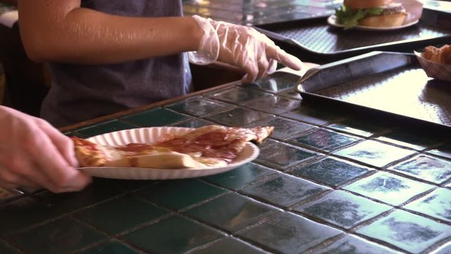 Pepperoni pizza slice being picked up from a counter