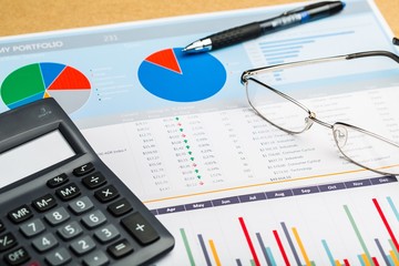 Pen, Eyeglasses and Calculator on Business Graphs and Charts