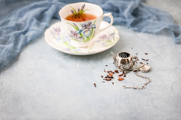 Royal Albert Iris Fine Bone China Tea Cup and Saucer with Herbal Tea and Tea Infuser on Blue...