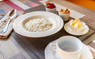 Healthy breakfast. Rice porridge bowl with berries and nuts on the table, hot and healthy breakfast food, side view