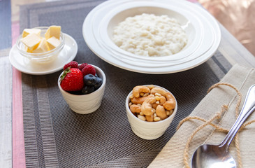 Healthy breakfast. Rice porridge bowl with berries and nuts on the table, hot and healthy breakfast food, side view