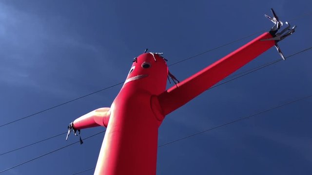 Red inflatable balloon man air dancer blowing in the wind