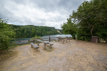 Fototapeta na wymiar Tables with benches on picnic area near lake in park