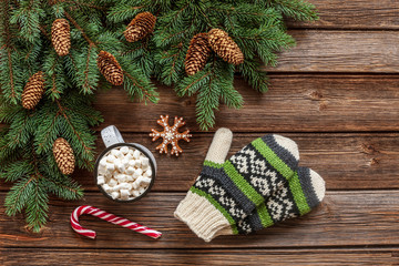Christmas  background with fir tree branches, cup of hot drink  with marshmallow and mittens. Christmas and New Year concept. Close-up, top view on vintage wooden table, place for your text