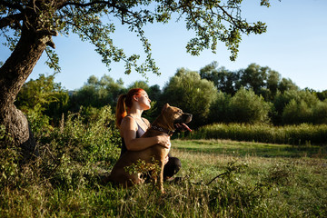redhair jouful young girl caressing her dog in park