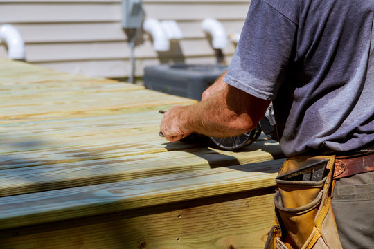 Backyard Deck Reconstruction handsome man carpenter installing wood floor new house