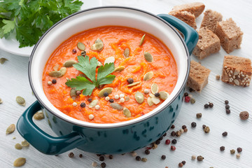 Pumpkin soup in a pot on white wooden background