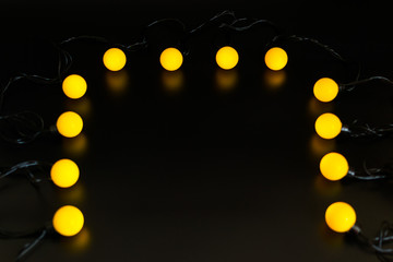 yellow glowing garland neatly straight-lined balls on a black background with light reflection
