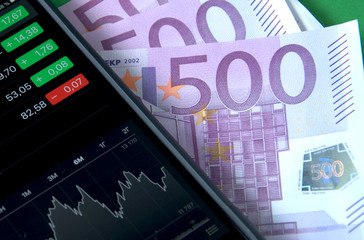 European Euro banknotes and smartphone, mobile trading.